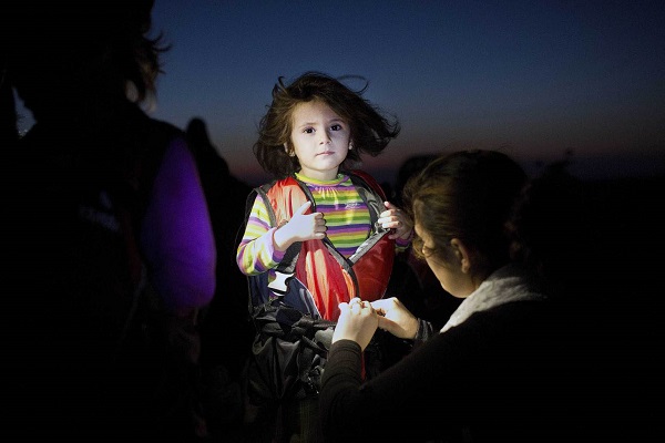 A child gets assistance to remove her life jacket upon her arrival on an inflatable boat carrying migrants on the Greek island of Kos after crossing a part of the Aegean Sea between Turkey and Greece on August 13, 2015. Greece sent extra riot police to Kos as tensions mounted over a huge influx of migrants. The Greek government said it was "immediately" dispatching a ship to Kos to double up as an accommodation and processing centre for up to 2,500 people as around 7,000 migrants wait to apply for immigration papers. AFP PHOTO / ANGELOS TZORTZINIS (Photo credit should read ANGELOS TZORTZINIS/AFP/Getty Images)