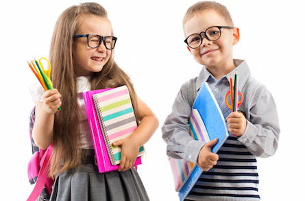 Two smiling school kids with colorful stationery, isolated on white background. School, education concept.